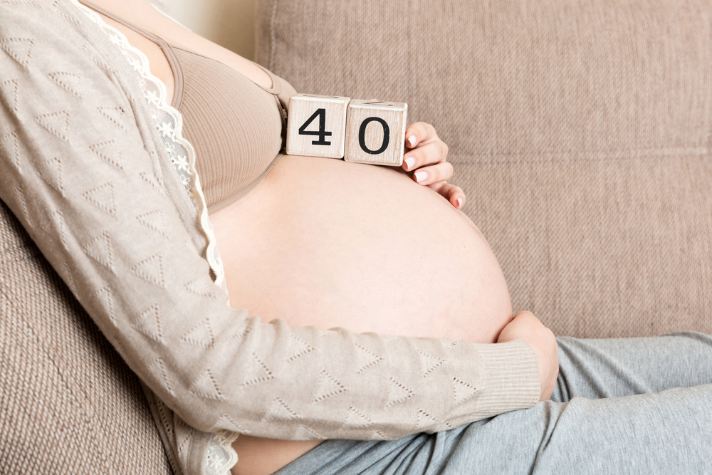 Donna incinta che compone il numero delle 40 settimane di gravidanza con dei cubi di legno sul pancione.