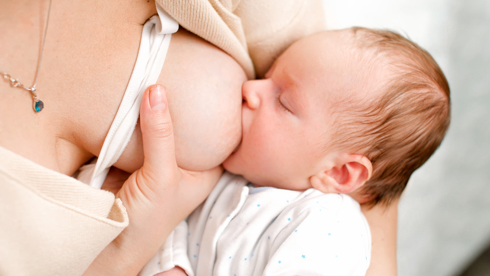 Donna afferra il seno per facilitare un corretto attacco del neonato.