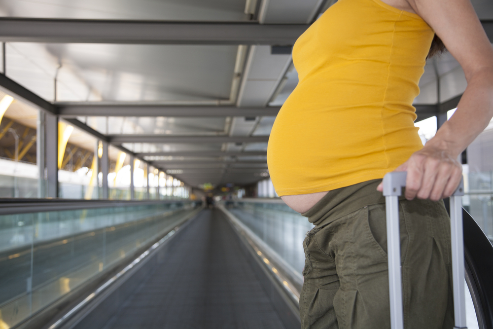 Viaggiare in gravidanza: una donna incinta con la valigia aspetta di partire