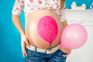 Donna incinta con palloncino disegnato sul pancione , come simbolo della pancia gonfia in gravidanza